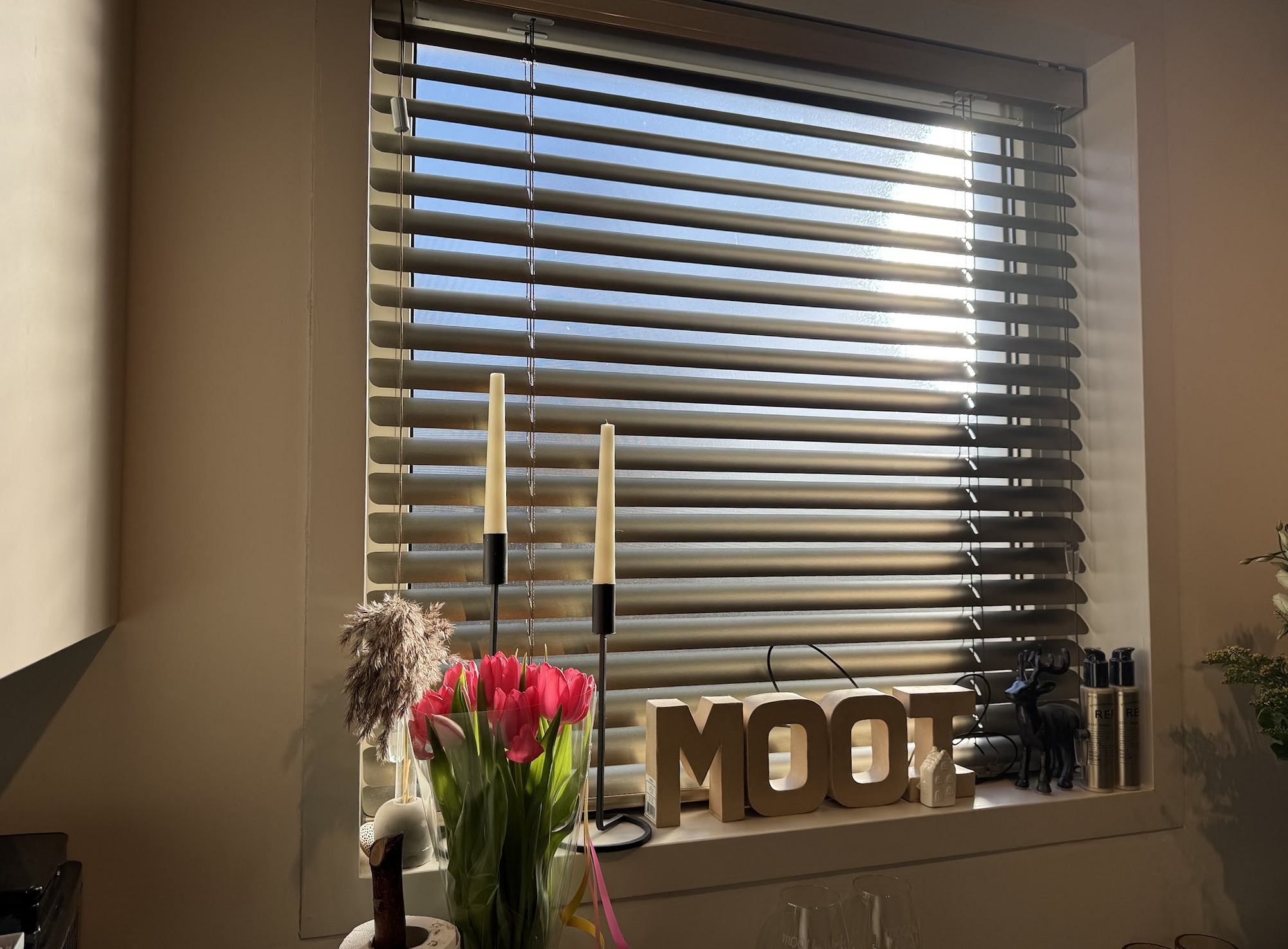 Het raam van de salon met tulpen, kaarsen en de letters MOOI in de vensterbank